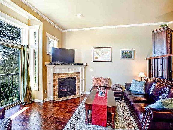 This living room has it all: rich, dark hardwoods, full-size sliders facing an expansive territorial view, and a corner, tiled-surround gas fireplace that capably heats both this level and the top floor Master Suite!  Note the upgraded details, like the crown molding and wrought iron separation between living and dining rooms.