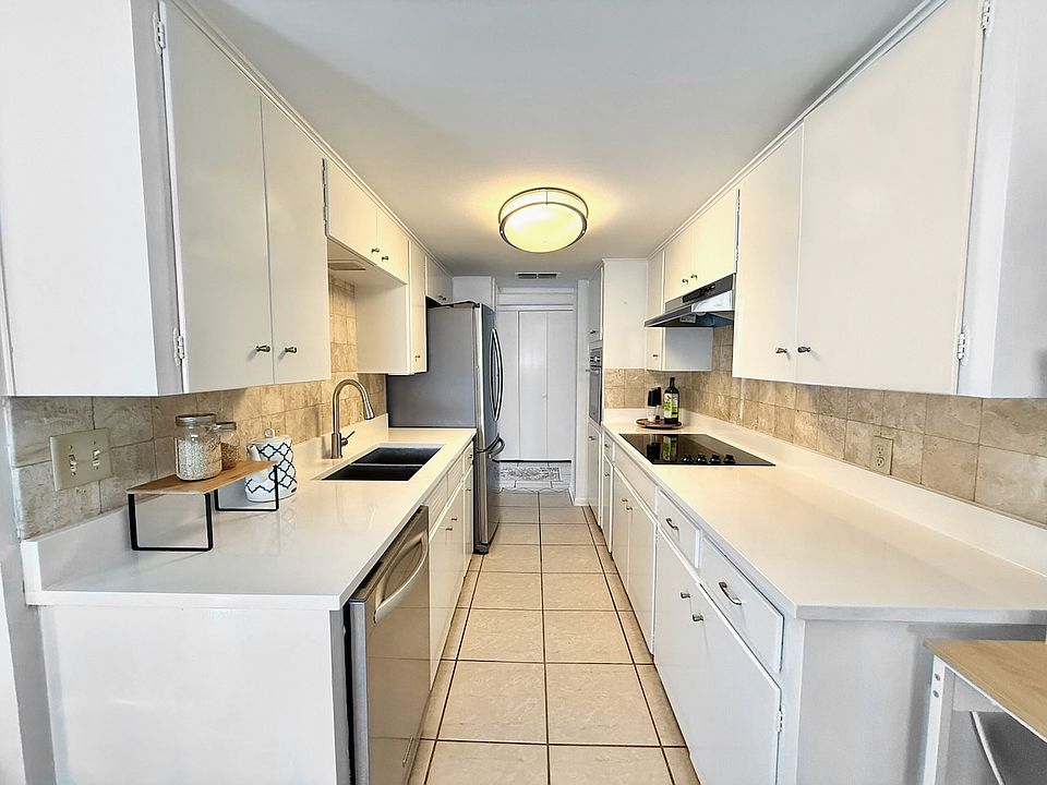 Kitchen with stainless French door refrigerator, stainless dishwasher, tile backsplash and floors, as viewed from breakfast nook. New 2025 white quartz counter, black glass cooktop, wall oven, stainless sink and faucet.
