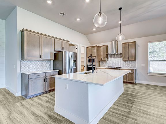 Designer kitchen with stunning cabinetry, an oversized island, and stainless appliances.
