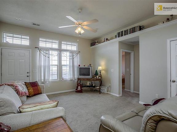 Living room with 10 foot ceiling, ceiling fan, carpet and a coat closet.