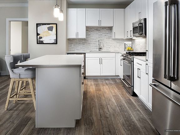 Signature Collection kitchen with white cabinetry, light grey quartz countertops, white marbled subway tile backsplash, stainless steel appliances, and hard surface flooring
