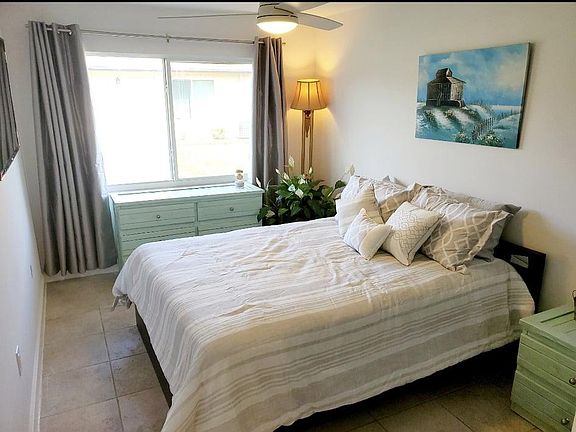 Bedroom with Double wide Windows offering lots of Natural Lighting, a remote Ceiling Fan and Flat Screen Television.