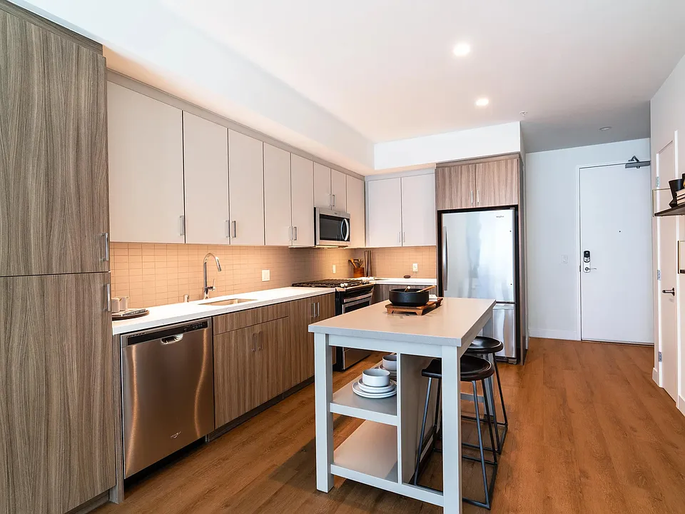 Kitchen with dual-tone cabinetry, stainless steel appliances, quartz surfaces, and a central island that adds flexibility for dining and meal prep.