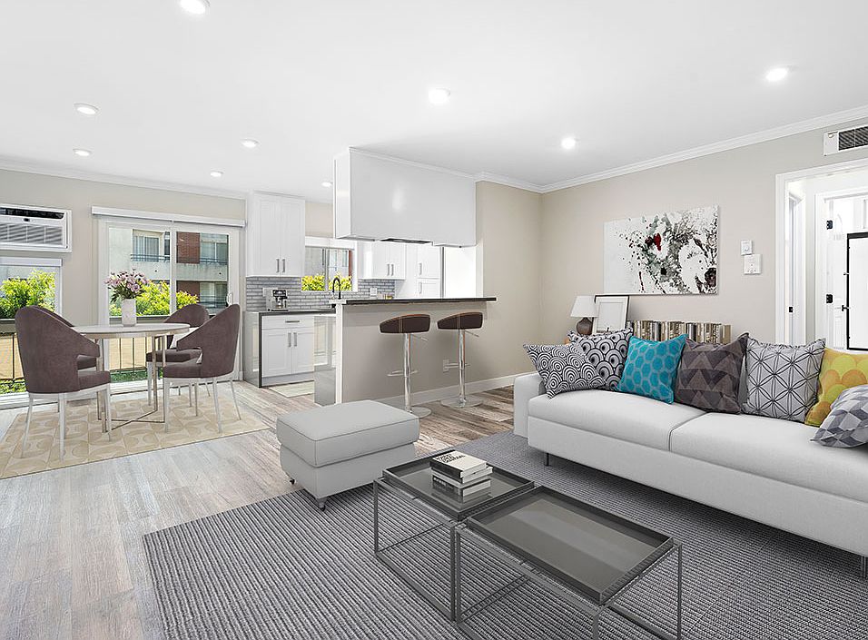 Hardwood floored living room with view of dining room, bar seating in kitchen, and balcony.