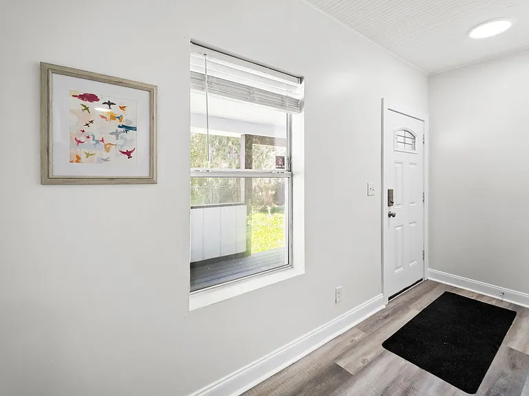 Welcoming entryway with durable wood-look flooring, large window, and space for a bench or shoe storage near the door.