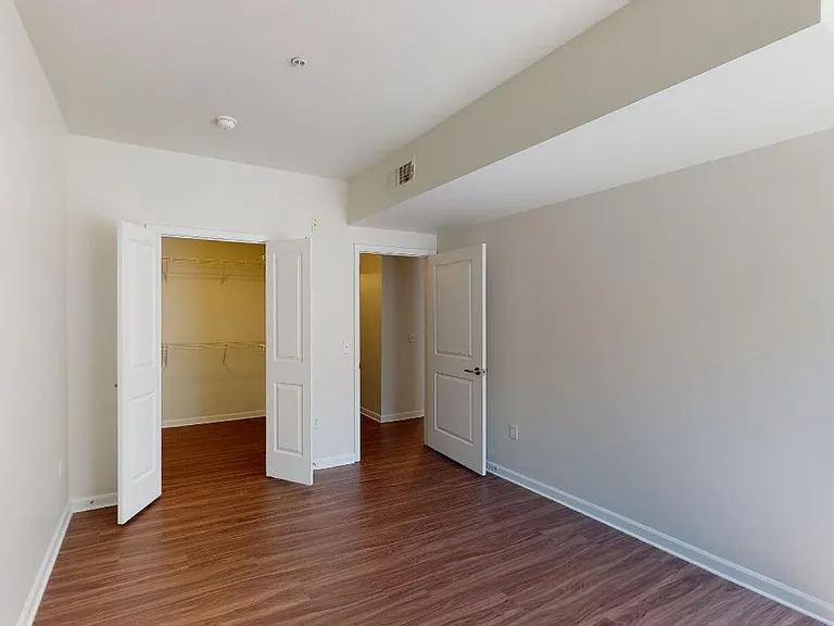 Spacious apartment bedroom with large closet and wood-style flooring.
