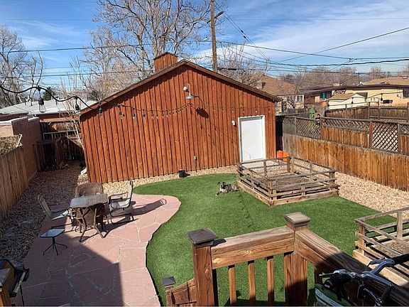 Backyard with flagstone patio, two raised garden beds, and artificial turf. Large garage can fit 2 cars and has additional room for storage.