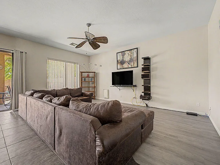 Spacious living room with a large sectional, ceiling fan, and TV area, plus sliding-door access to the patio.