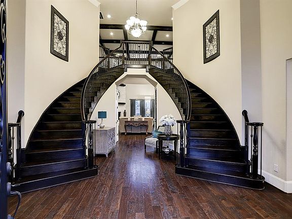 Step inside to find hardwood floors, twin sweeping staircases with wood treads & railings and ornate iron spindles, soaring ceilings, thick crown molding, and a stunning chandelier.