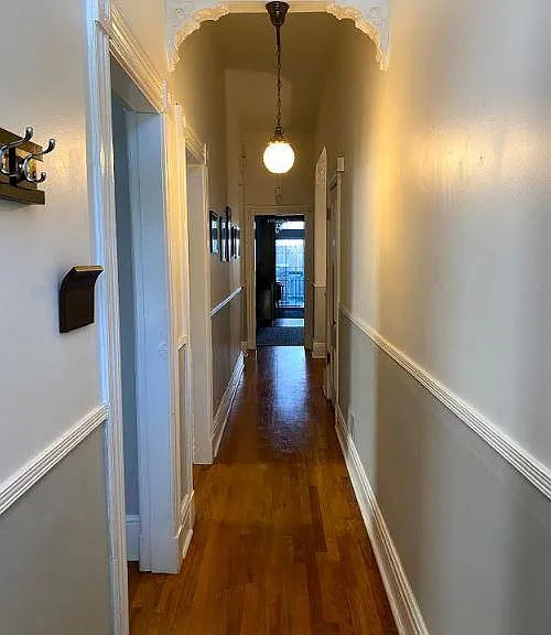 Hallway entrance fro front door leads to kitchen and deck. To the left is the living room, then the 2nd large bedroom. On the right is a large walk in closet and alcove perfect for a desk. Victorian light fixtures and details throughout the home.