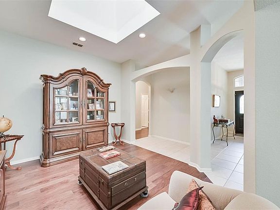 Living room with a skylight, arched walkways, light wood-style flooring, visible vents, and recessed lighting