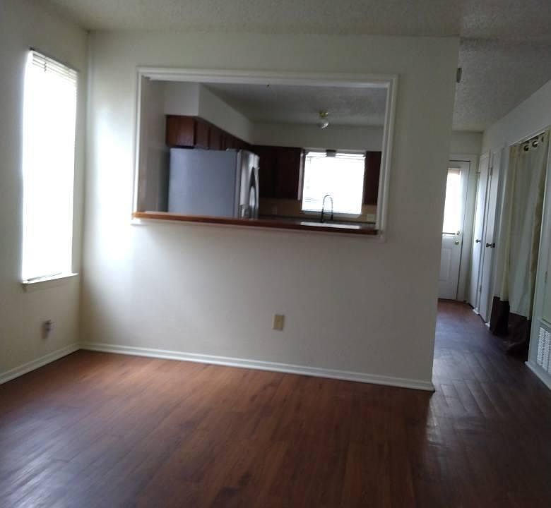 This is the entry living room that looks into the kitchen area. There is a fireplace on the window side of the wall. There is 3 windows on the one side wall in the living room.