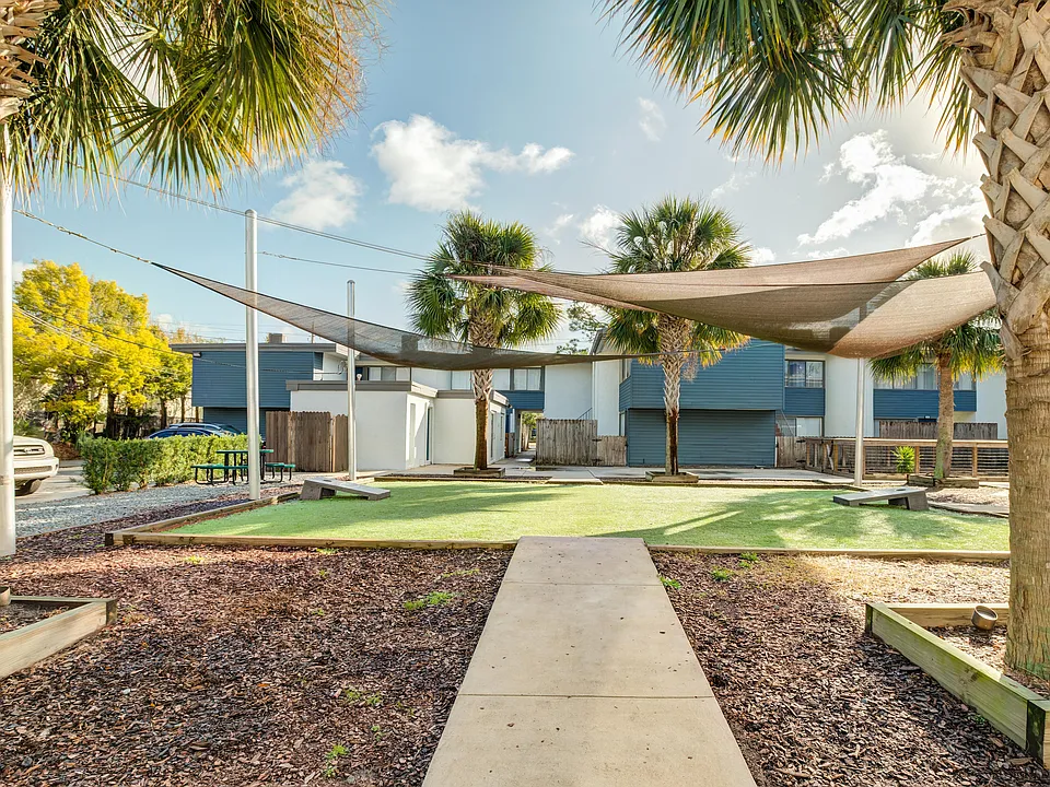Charming outdoor space with palm trees and shade sails, perfect for relaxation and leisure.