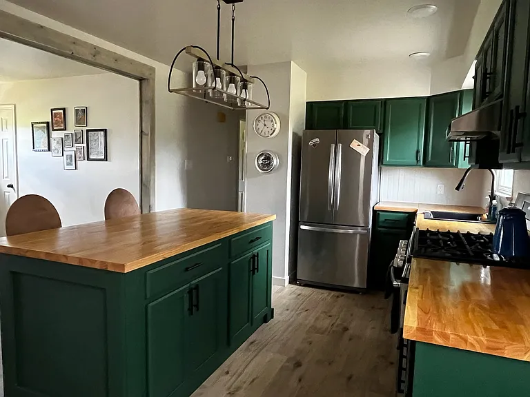 View into kitchen, complete with gas range and stainless steel appliances and deep farm sink