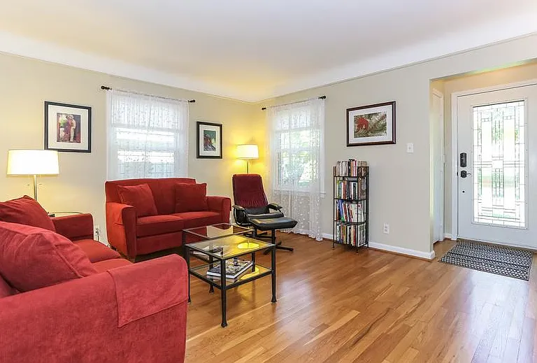 The living room looking back to the leaded front glass door. Plaster walls, cove ceilings and beautiful hardwood floors all add to the charm of this home.