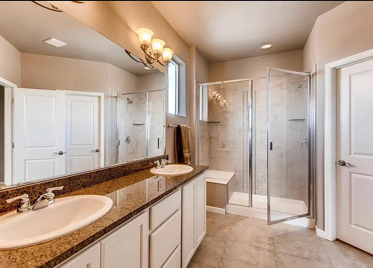 Primary bathroom with dual vanity, separate toilet area, walk in closet and walk in shower with shower bench.