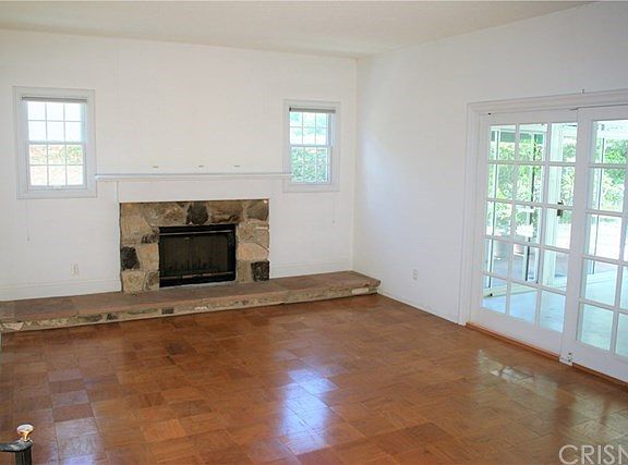 Step down formal living room with stone fireplace. Custom dual pane windows & wood slider.