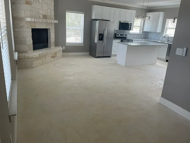 Living room with limestone wood burning fireplace, granite counters and stainless steel appliances.