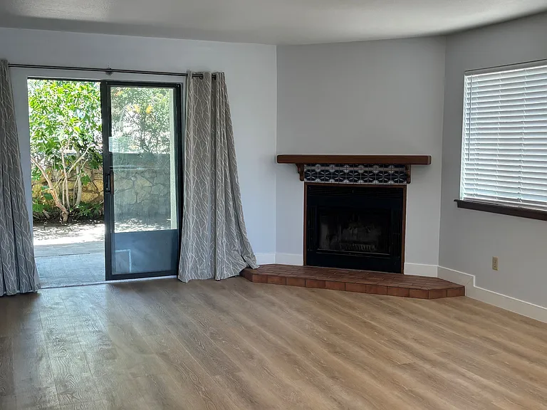 roomy and bright living room with fireplace and lots of windows with slider to back patio
