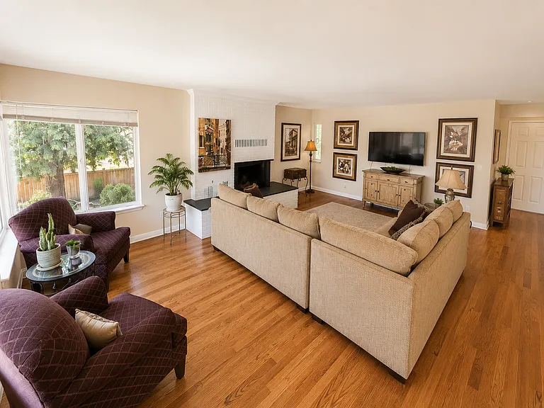 Large open living room with hardwood floors, wood burning fireplace, and huge windows