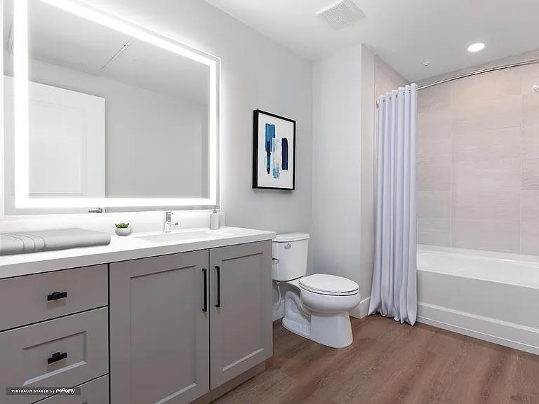Signature Collection bath with grey cabinetry, white marble countertop, backlit mirror, and hard surface flooring