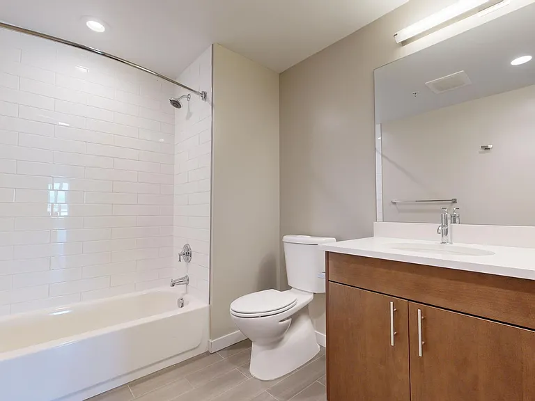 Apartment bathroom with wood-style flooring.