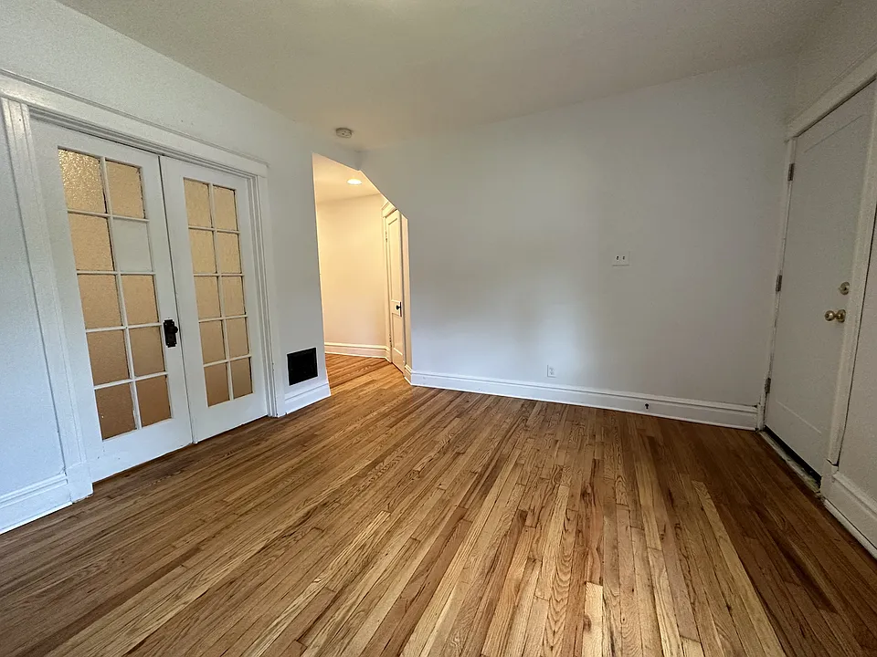 Living room, wood floors, French doors into bedroom, allows bedroom to be converted to office/etc.