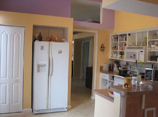 White appliances in kitchen with volume ceilings and sliders to pool area 
