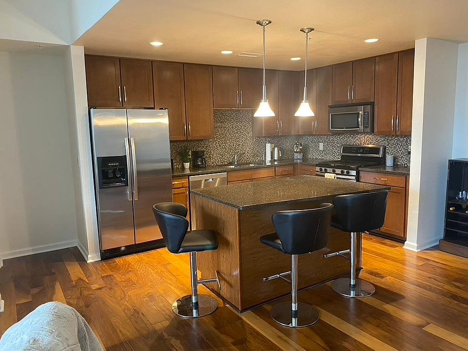 Open and spacious kitchen with bar, stools, granite countertops, cherry wood floors