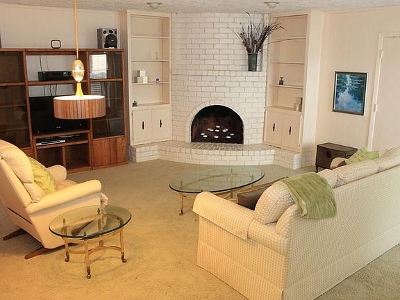 Den features corner brick fireplace w/built-in shelving on both sides and plenty of room for all your furniture.