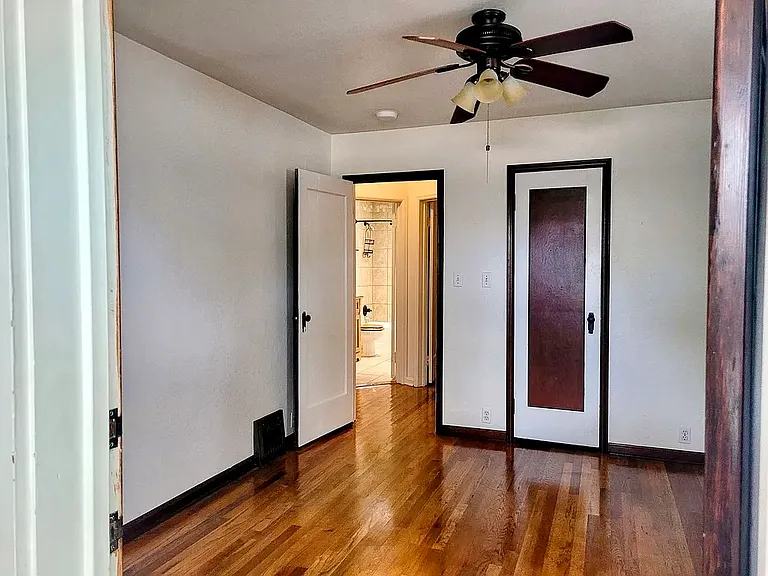 Primary bedroom. Picture taken from front porch. Door on right into closet. Open door leads to hallway and bathroom.