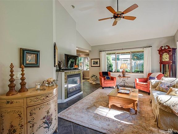 The light-filled living room features a propane fireplace, ceiling fan and vaulted ceilings.