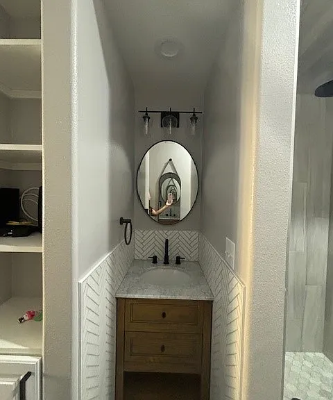 Sink with mirror and full-length mirror on the wall behind.