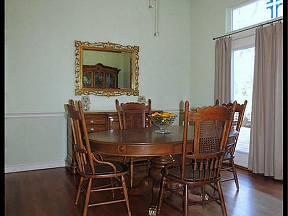 Formal dining room with hardwood floors, ceiling fan and double glass doors leading outside. One door is stationary while the other one opens.