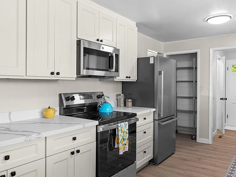 Galley-style kitchen with ample cabinet storage, quartz-look counters, and stainless steel range, microwave, and fridge.