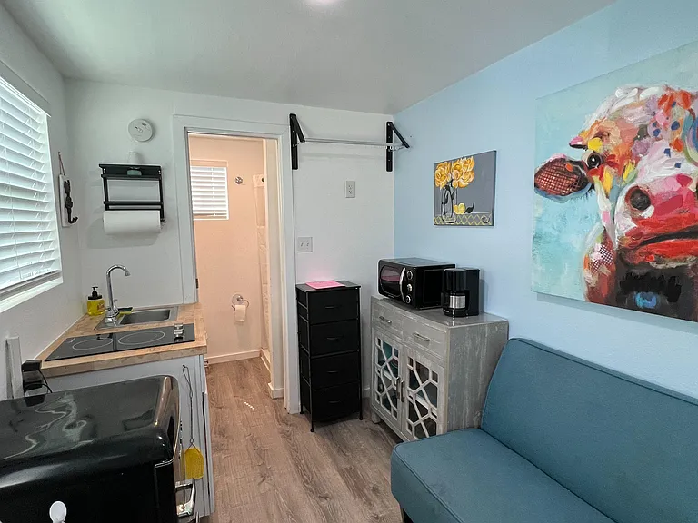 Efficient kitchenette with sink and cooktop, plus a compact lounge area. 4 drawer dresser and clothes hanger above.
