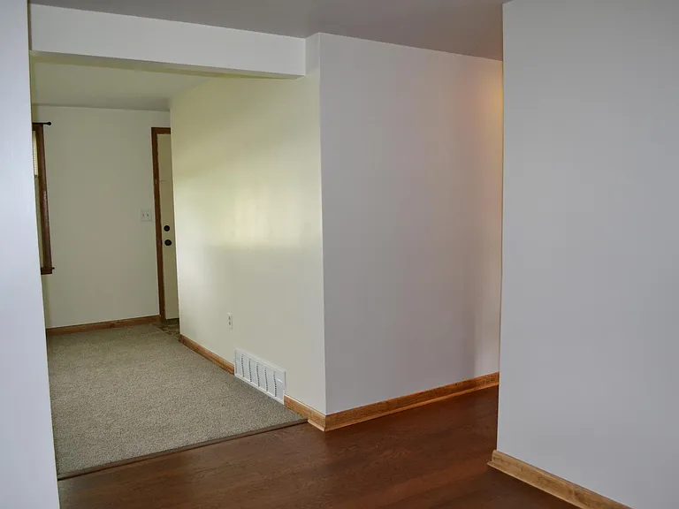 View from dining area toward front of house and living room. Hall to the right leads to bedrooms. Door peeking out in the front room exits to front yard.