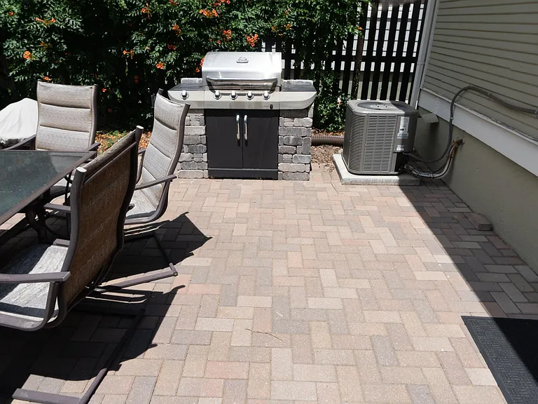 The backyard patio with table and chairs, BBQ grill and the air conditioning unit is right of the grill.