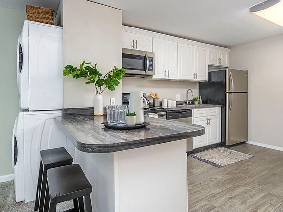 A versatile kitchen with a convenient breakfast bar, perfect for cooking, studying, or folding your laundry. The centrally located full-size washer and dryer is perfectly placed for ultimate convenience.