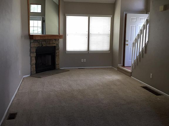 Living room with wood-burning fireplace, and dining room with hardwood flooring.