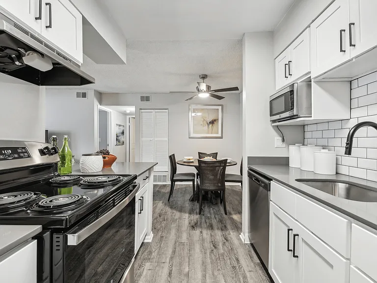 Modern kitchen with white cabinets, black appliances, and a dining area