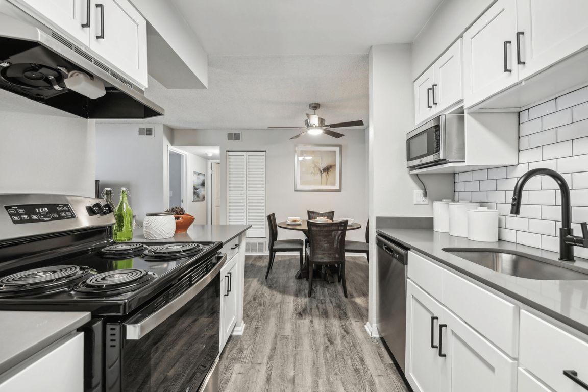 Modern kitchen with white cabinets, black appliances, and a dining area