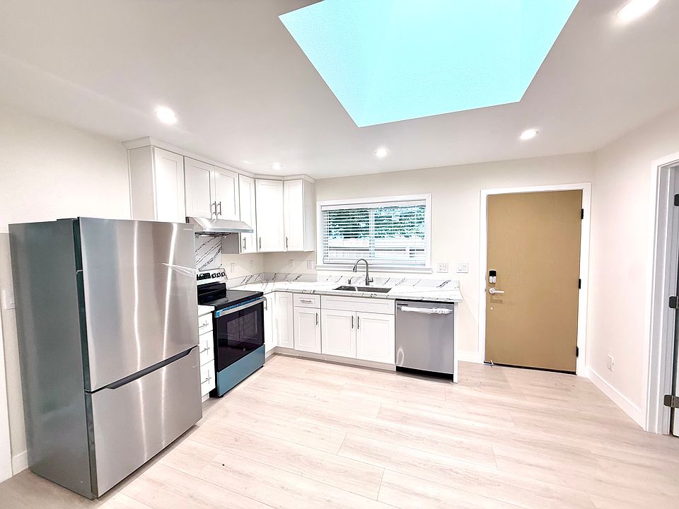 Living room with brand new kitchen appliances, customized cabinets and countertop, in-unit washer and dryer, and skylight roof window for perfect lighting