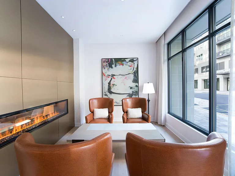 A cozy lounge at Modera Liberty Row features a modern fireplace, comfortable seating, and natural light for relaxed moments throughout the day.