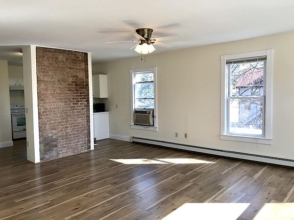 Living room with 4 large windows, 2 full size closets. Exposed brick partial wall separates living room from kitchen.