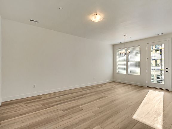 Minimalist empty room with wooden floor, white walls, a ceiling light, and a windowed door letting i
