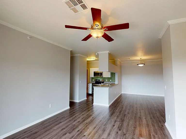 Apartment kitchen, dining and living room with wood-style flooring.