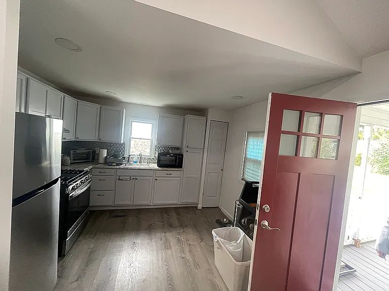 Kitchen with Stainless steel appliances, light countertops, white cabinetry, and decorative backsplash