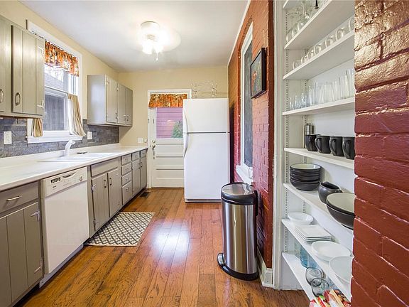 This kitchen keeps the old-world charm with the original exterior brick wall now re-purposed with modern built-in open shelving and a chalkboard to keep you organized or the kids entertained while you cook.