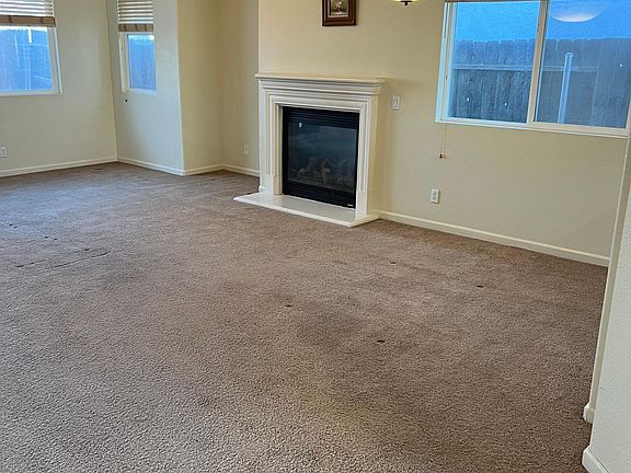 Living room with natural light, gas fireplace, and ceiling fan